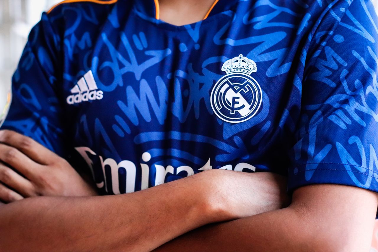 Crafting Captivating Headlines: Your awesome post title goes here Arms crossed in a vibrant blue sports jersey with team logo and abstract pattern design.